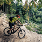 Ciclista con bicicleta de montaña en un camino rodeado de vegetación